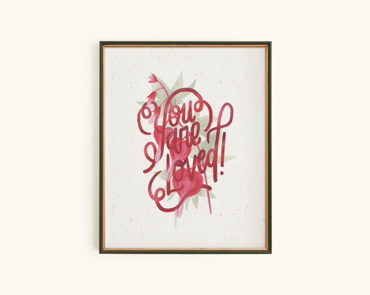 Framed artwork with red text stating "you are Loved" and bleeding heart design on a creamy white background